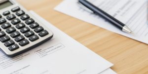 Calculator and tax documents on a wooden desk.